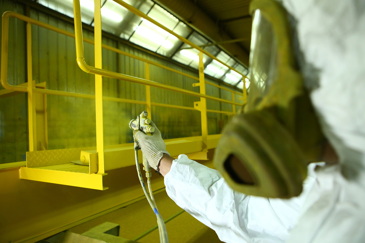 Metal Fabrication Paint booths. The painter paints the iron element in yellow. Metal Fabrication Paint booths